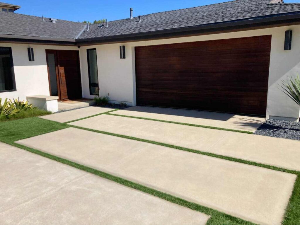 Modern home facade featuring a stylish entrance, wooden garage doors, and a neatly landscaped driveway with grass accents.