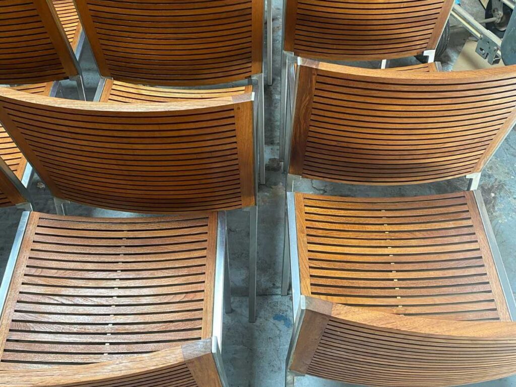 A close-up view of modern wooden chairs with slatted backs, arranged closely together, showcasing their elegant design.