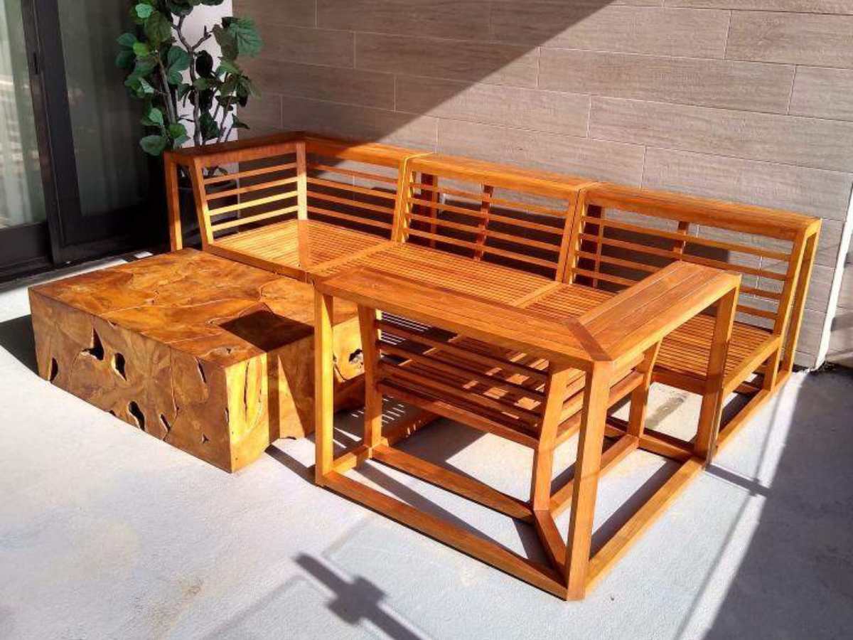 A stylish outdoor seating arrangement featuring a wooden sectional sofa and a unique, rustic table with natural textures.